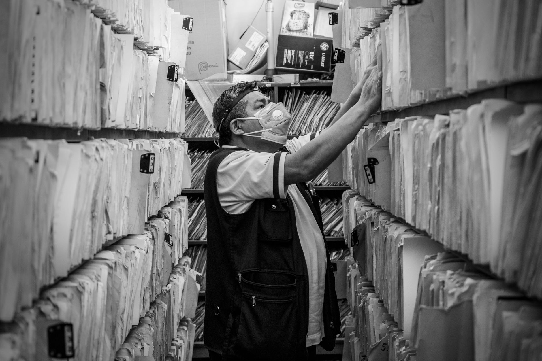 Person retrieving a file from archive shelves